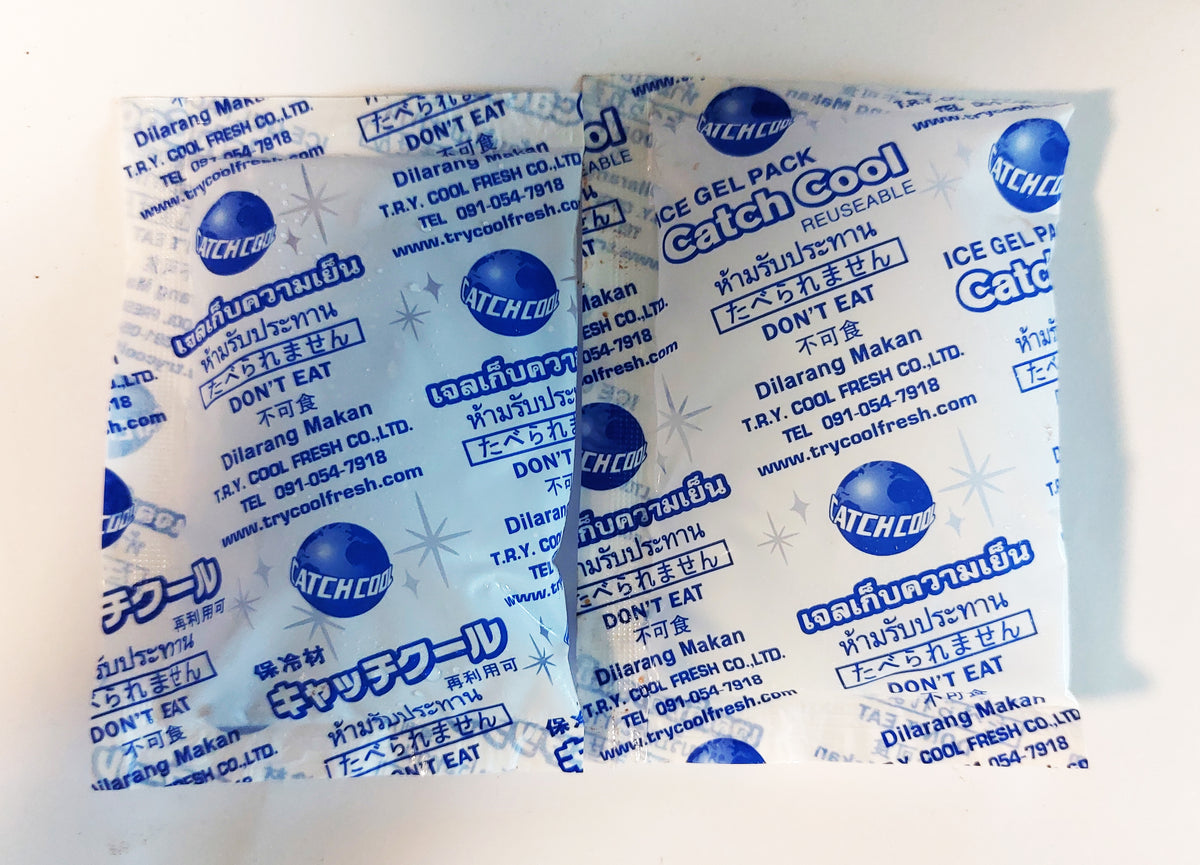 Two soft plastic gel cold packs lying flat on a white surface, printed with blue text and a snowflake pattern